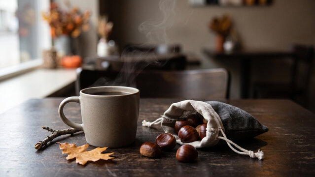 Steaming Mug and Chestnuts on Wooden Table in Autumn