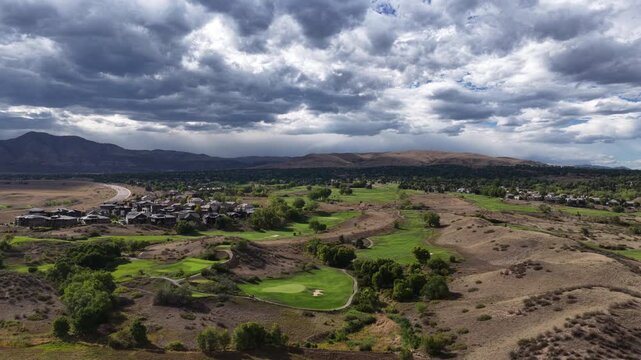 Aerial of golf course and residential community in Jefferson County Colorado nestled among housing developments with stormy dramatic sky over the front range mountains