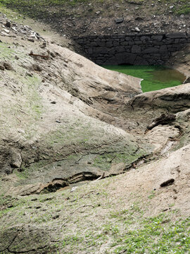 ORLIK RESERVOIR, CZECH REPUBLIC - AUGUST 7, 2026: Extremely low water levels at Orlik Dam, cracked muddy ground, green algae, and an old historic stone bridge normally submerged underwater.