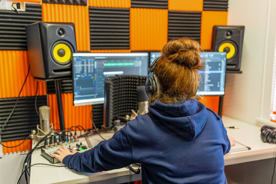 Young female audio producer working at radio station workstation