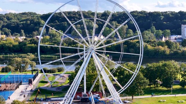 Aerial drone footage of a Ferris wheel under construction on Nemunas Island in Kaunas, Lithuania, showing a new observation attraction rising in the city center. 4K video 