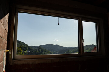 Fototapeta premium Modern window frame with a view of trees in a house under construction
