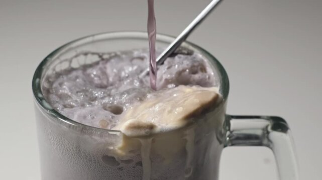 Pouring grape soda over ice cream to create a float.
