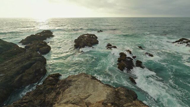Pacific Ocean waves break around rocky bluffs in Fort Bragg at sunset