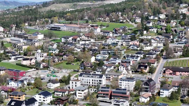 dense residential rooftops vaduz outskirts swimming pool playground green field building complex forested hillside vineyard edge liechtenstein drone footage aerial view elevated view small town