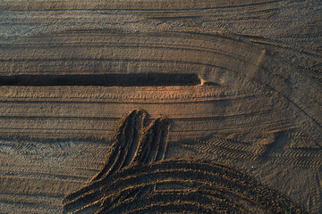 Fototapeta premium Aerial top down view of tire tracks and machinery marks on dark soil in an industrial peat harvesting field in Estonia.
