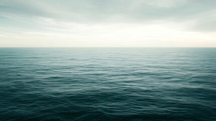 Fototapeta premium Ocean surface meets deep blue sea with cloudy sky overhead.