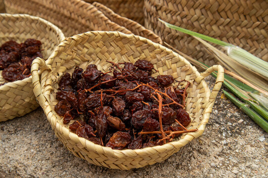 Handwoven wicker basket filled with dried brown raisins after sun drying in a local market