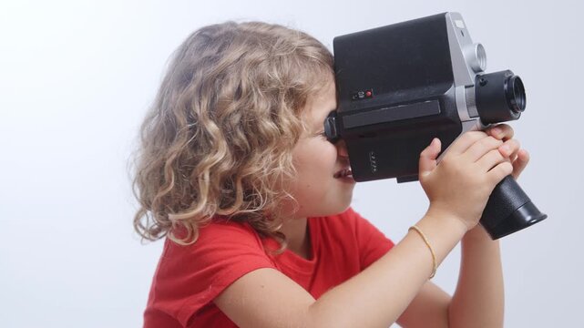 small girl looks with vintage film camera