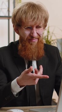 Young bearded businessman working on laptop computer shakes finger and saying No be careful scolding and giving advice to avoid danger mistake disapproval sign at home office. Confident freelancer man