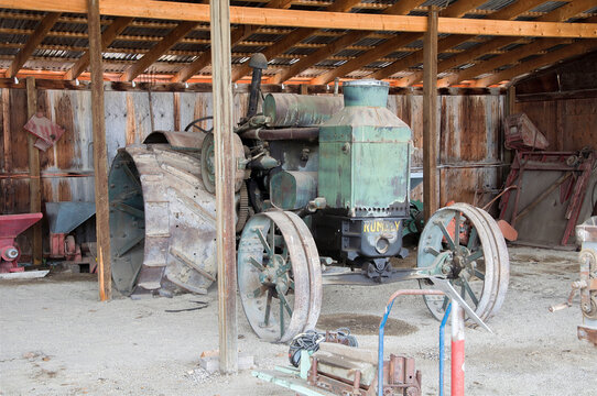 IRRICANA, CANADA - 08 AUGUST 2026: A vintage green Rumely OilPull tractor with large steel wheels stored inside an old wooden barn.