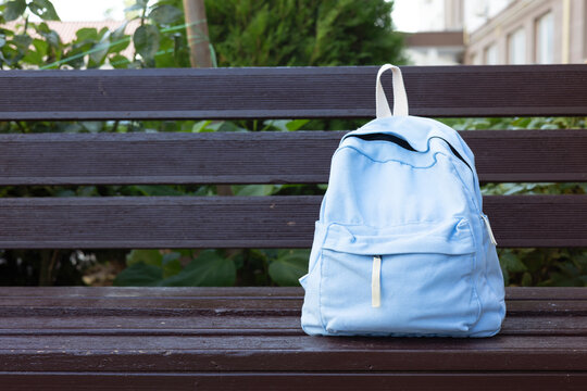 School backpack on park bench outdoors. Back to school education concept 
