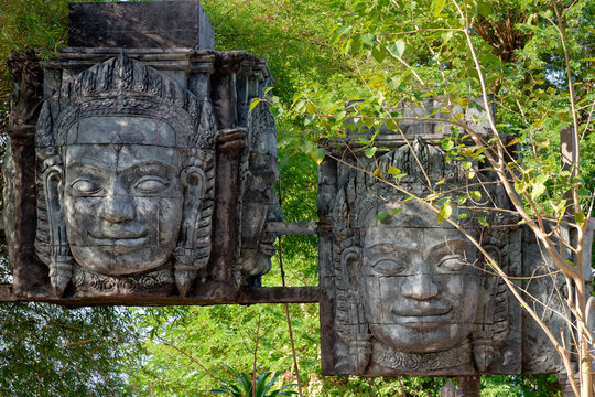 Khmer style stone face sculptures among green foliage in Thailand