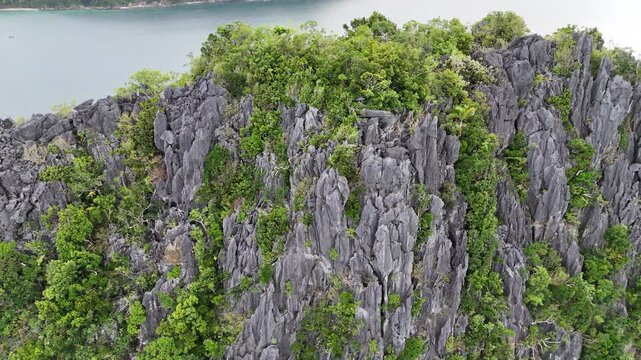 The scene shows palawan&rsquo;s dramatic rock landscape fills the aerial frame and deep blue water beyond the rocky shoreline in El Nido, Palawan, Philippines.