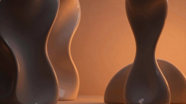 three vases different shapes sizes arranged row wooden surface vases ceramic smooth glossy finish first vase dark grey color second light beige color third lighter shade beige three vessels curved