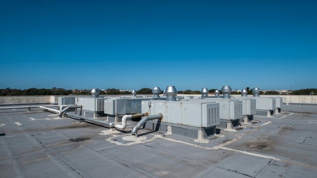 Row of large HVAC units lined across a flat rooftop under a deep blue cloudless sky