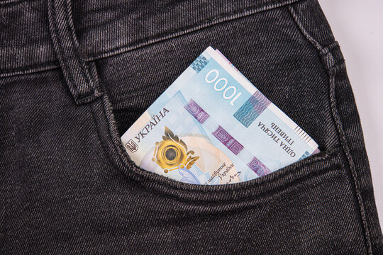 Ukrainian money, specifically a 1000 hryvnia bill protruding from jeans pocket, symbolizing economy and finance, vibrant banknote against dark denim fabric, casual everyday setting, intricate design