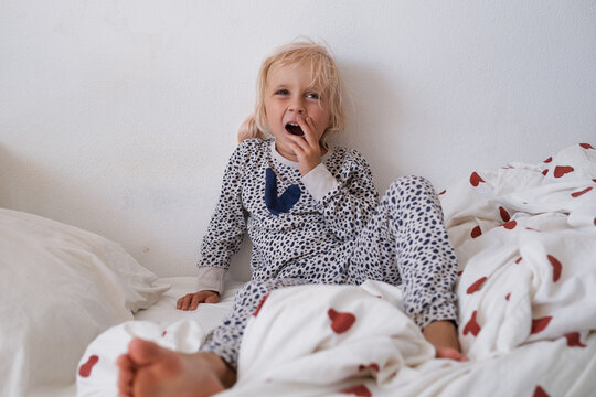 Angry little girl crying and throwing stuffed toy in bed