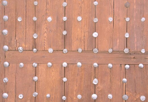 Old wooden door with rows of decorative metal studs