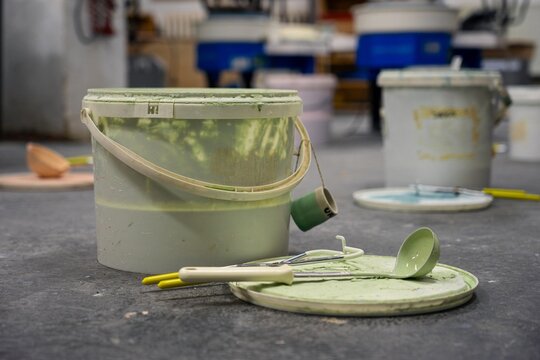 Green ceramic glaze bucket and dipping tools in a pottery studio