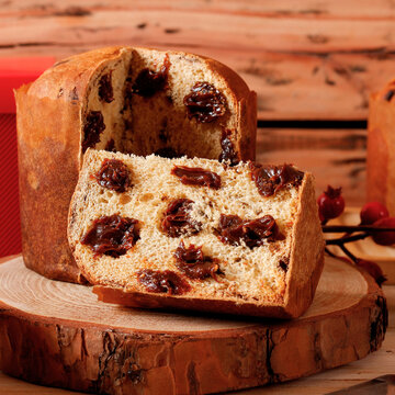 Sliced ​​Christmas panettone with creamy chocolate filling on a rustic wooden table during a Christmas celebration.