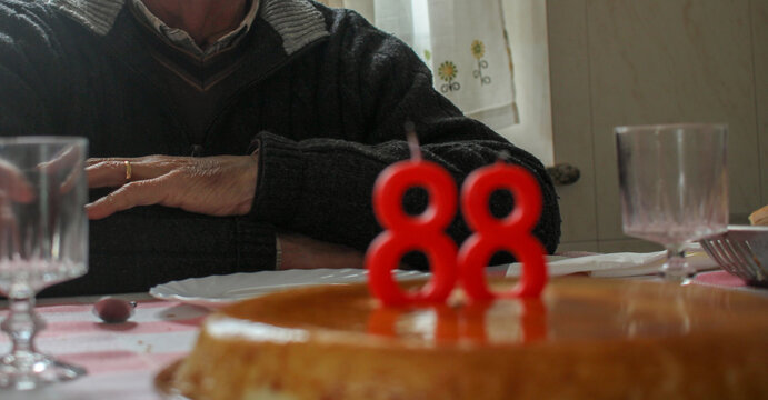 Senior man celebrating 88th birthday with cake and candles at home