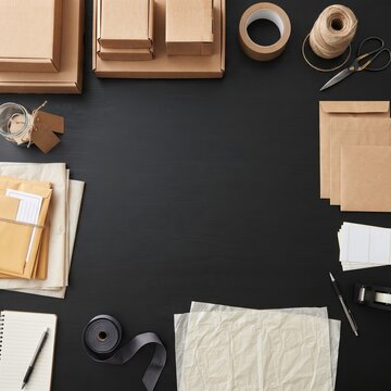 Shipping and packaging supplies are laid out neatly on a dark surface, showcasing a variety of materials for sending parcels and gifts, perfect for e-commerce or small business needs.