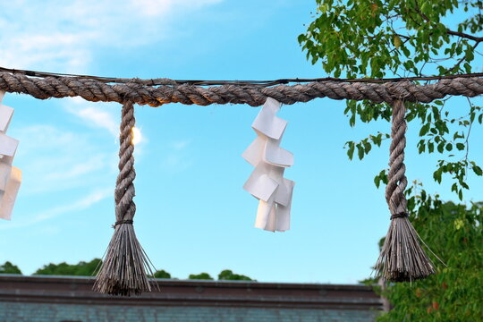Shimenawa rope with shide against blue sky in Japan