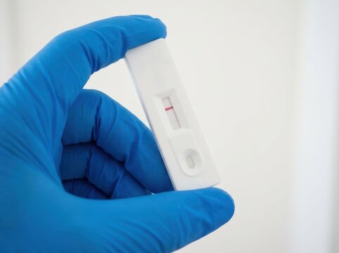 Gloved hand holding a rapid antigen test device showing a negative result for diagnostic medical testing