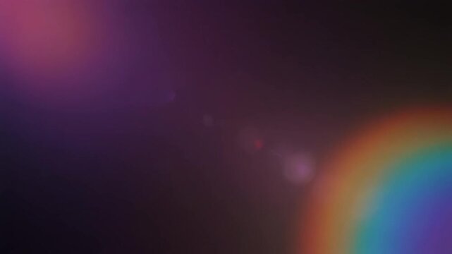 Soft rainbow prism light and lens flare sweeping across dark background