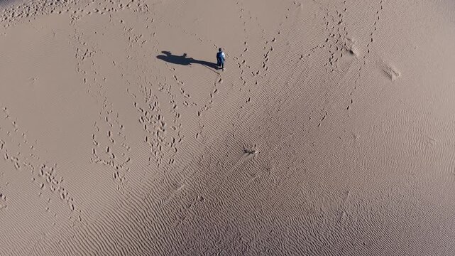 Aerial view of lone traveler walking across Tengger Desert dunes