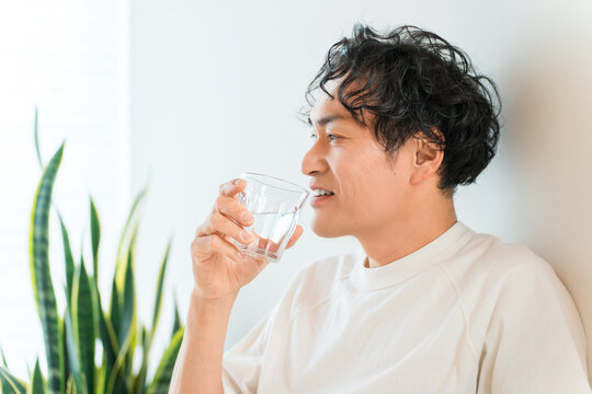 自宅で水を飲み水分補給する爽やかな男性