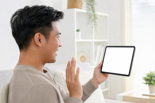 Young man waving hand during video call holding digital tablet