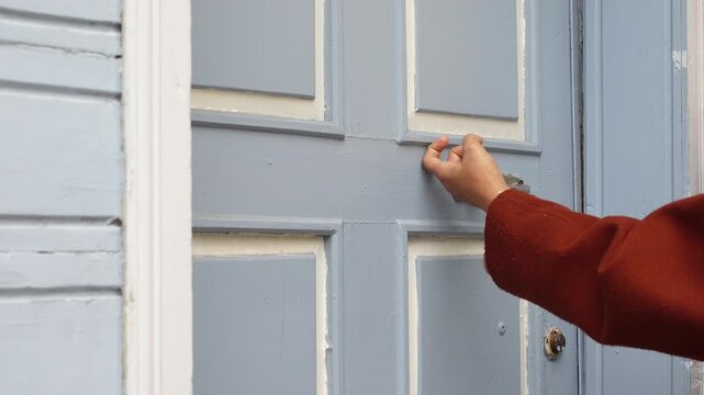 Close up video of person knocking on old wooden door with handle in rustic house