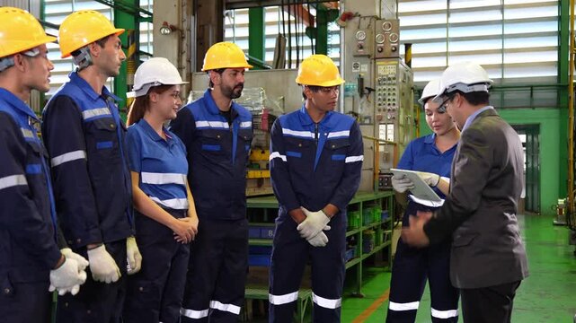 Diverse factory workers and manager attending briefing meeting in heavy machinery facility, Manufacturing team and supervisor standing together and discussing production in industrial plant