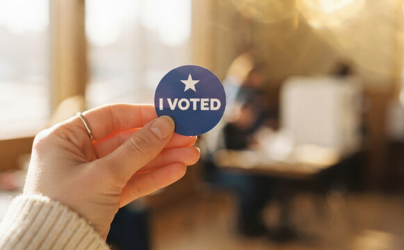 Young adult woman holding an I Voted sticker at a polling place for election day democracy