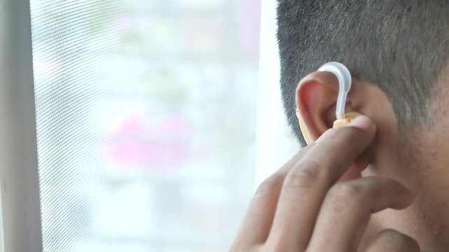 Person adjusting hearing aid in ear close up, understanding sound