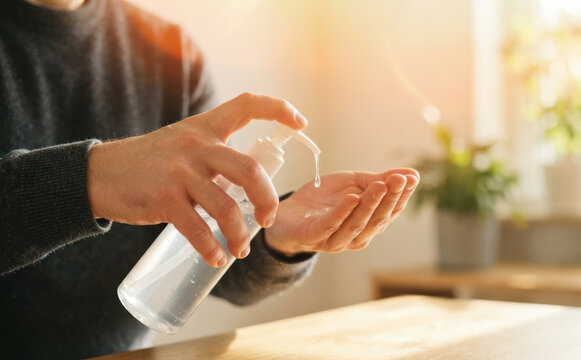 Man using hand sanitizer gel for hygiene and protection against germs, health and safety concept