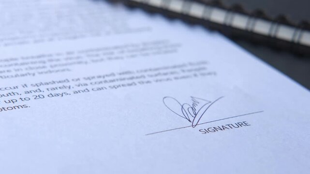 Person signing formal document on white paper with silver pen close up view of hand signature process