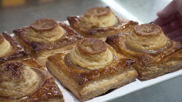 Removing a tray of flanesa pastries from a glass bakery counter