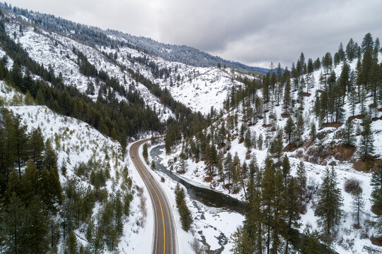 Winter road snakes through snow-dusted pine forests