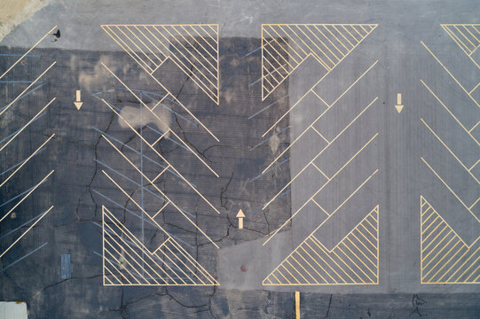 Cracked pavement marked with faded directional arrows and angular shapes
