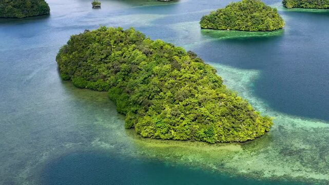 Aerial view of lush green limestone islands in crystal clear blue waters of Palau rock islands.