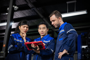 Technician team reviews digital vehicle diagnostics on tablet inside ev garage with focused collaboration and concern © 220 Selfmade studio