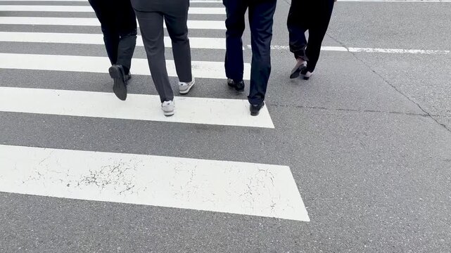 Low angle view of businessmen walking on pedestrian crossing in city center during daytime.