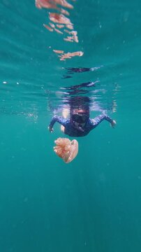 Woman swimming underwater with a jellyfish in togean, indonesia