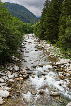 A view up the Avers Rhine river in the Magic Wood climbing area of Ausserferrera, Switzerland with a clearing storm in the mountains beyond