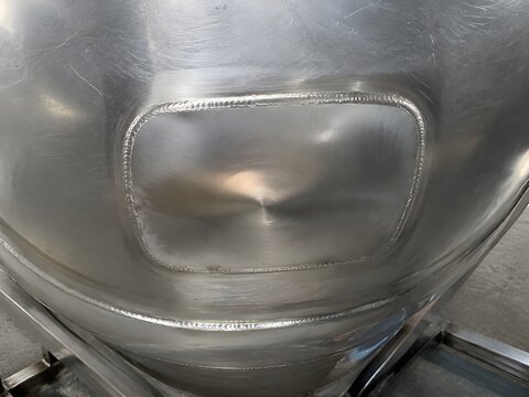 Finished stainless steel vessel repair with polished welded patch blending into surrounding metal