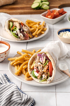 Street food and fast food dining, chicken gyro pita wrap with french fries and tzatziki sauce on a rustic table for a casual lunch or dinner meal