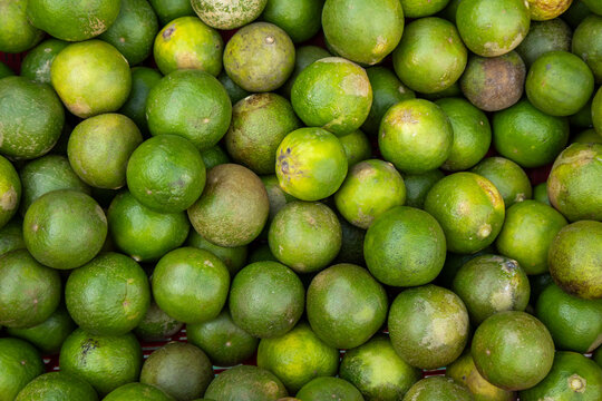 Fresh green key limes piled together at a traditional local street market.